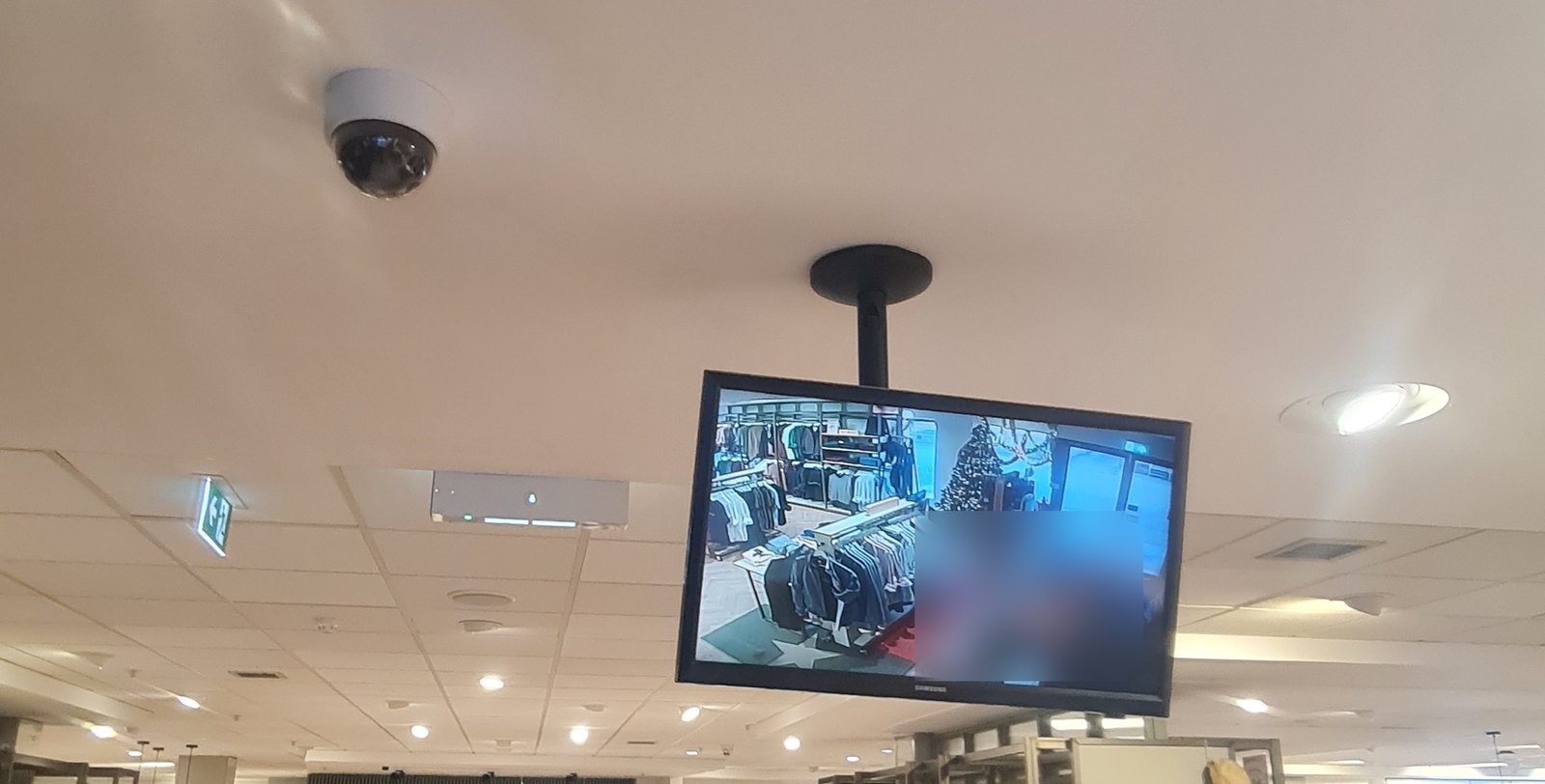Ceiling dome CCTV camera and a public view monitor showing the live camera picture on a shop floor