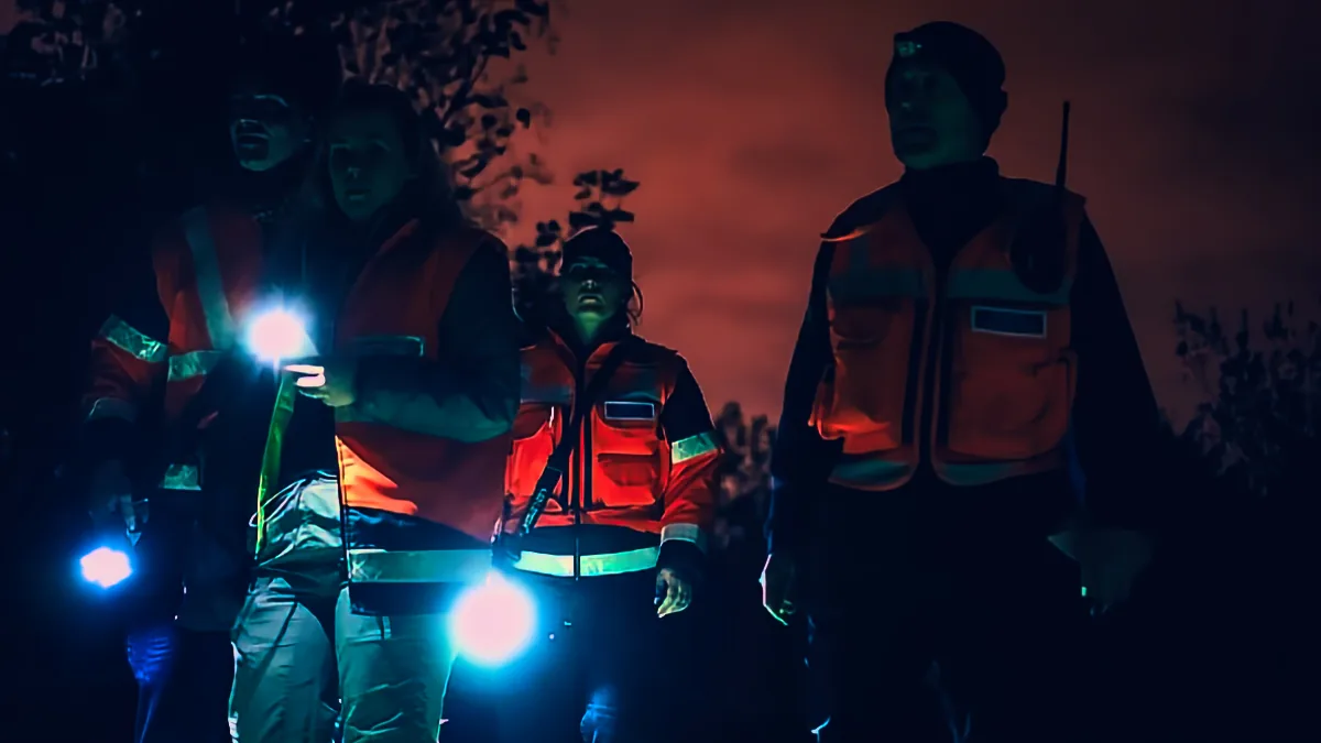 Search and rescue volunteers in high visibility jackets searching with torches at night