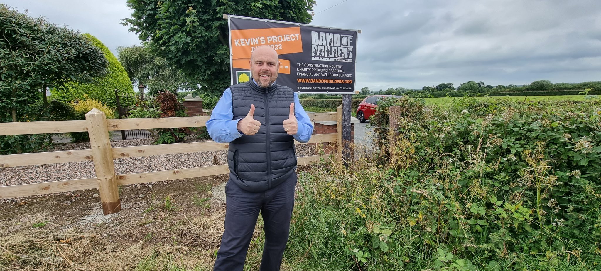 A participant beside the Band of Builders sign for the 2022 project