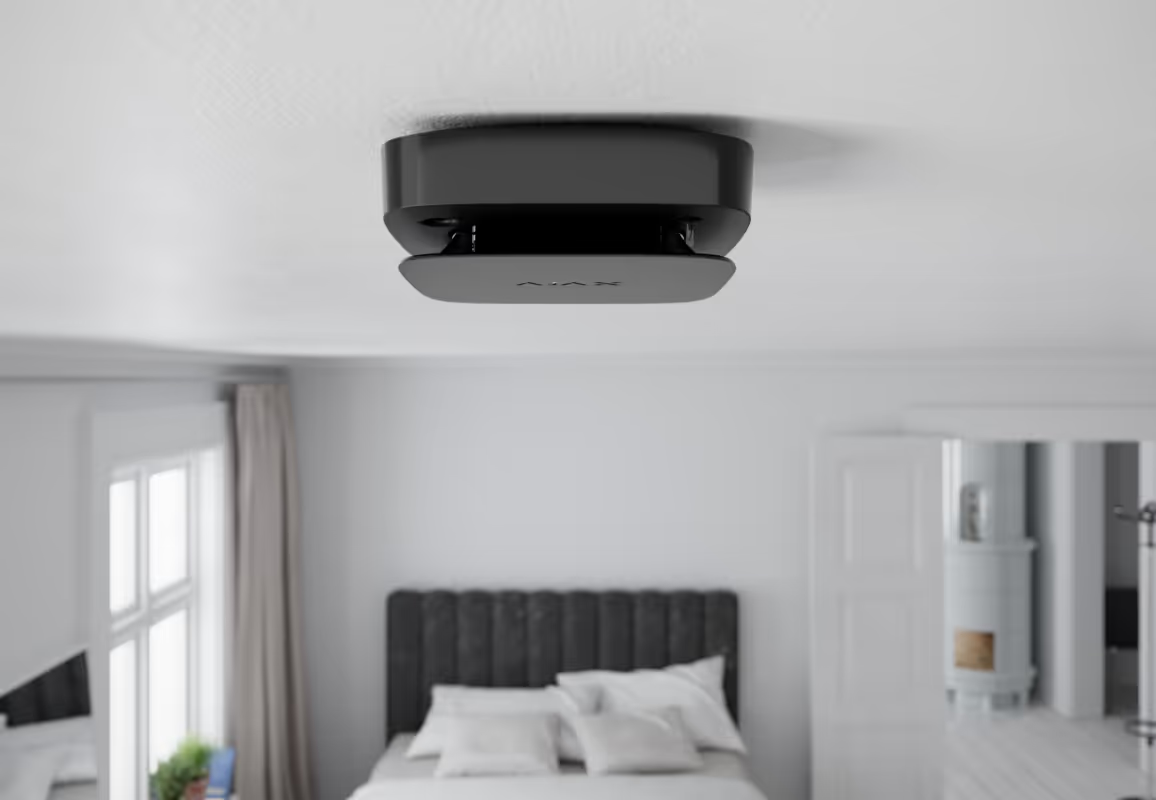 Black ceiling-mounted fire detector in a bedroom